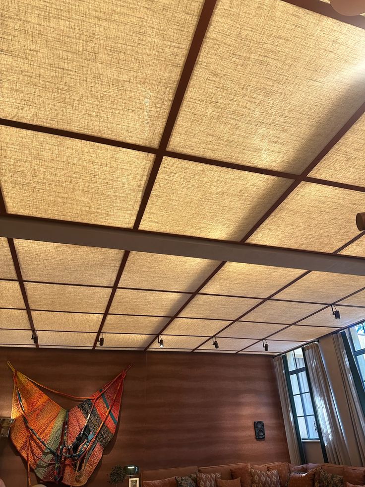 Warm interior space featuring a grid-style drop ceiling with backlit panels and exposed beam framing, creating a soft ambient glow above the wood-paneled living area.